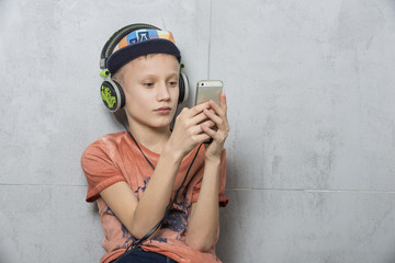 Chłopiec w słuchawkach słucha muzyki z telefonu komórkowego