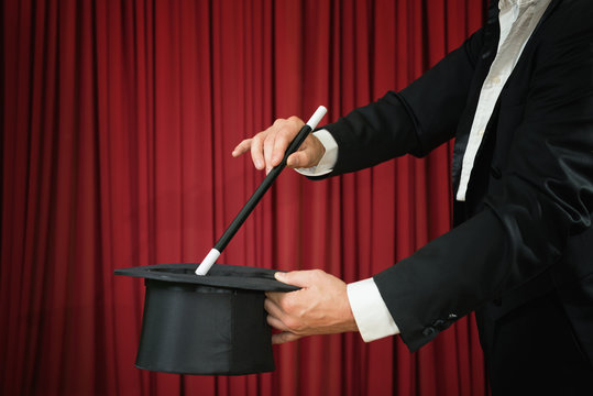 Magician with top hat and magic wand performing on stage