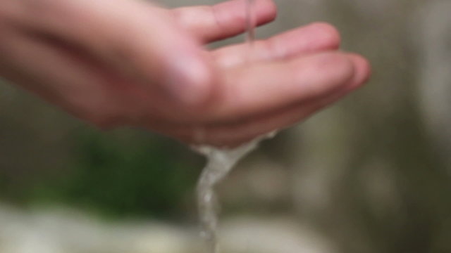 Wet Hand of a Man down the Running Water of a Fountain in a Mountain. Shallow Deep of Field.