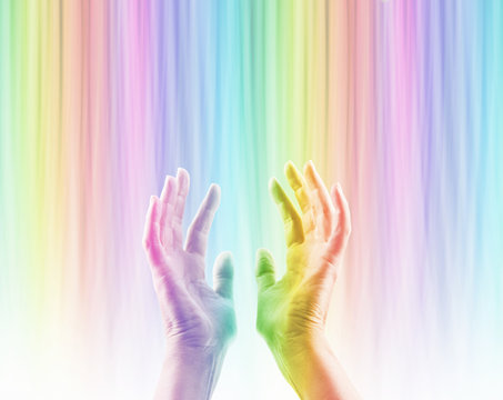 Absorbing Color Light Therapy - Female hands reaching up into rainbow colored light streaming down causing hands to become rainbow colored whilst absorbing the colored light