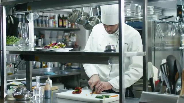 Professional chef in a commercial kitchen is slicing green vegetables. Shot on RED Cinema Camera.