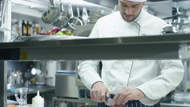 Professional chef in a commercial kitchen in a restaurant or hotel is slicing green vegetables. Shot on RED Cinema Camera.