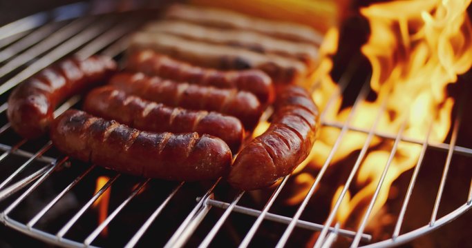 Sausages grilling over the flames on a summer barbecue in a close up view of a healthy outdoor lifestyle