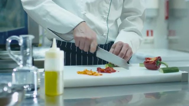 Professional chef in a commercial kitchen is slicing green vegetables. Shot on RED Cinema Camera.