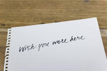 "wish you were here" hand written on white paper