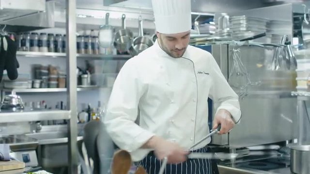 Professional chef in a commercial kitchen in a restaurant or hotel is sharpening knifes. Shot on RED Cinema Camera.