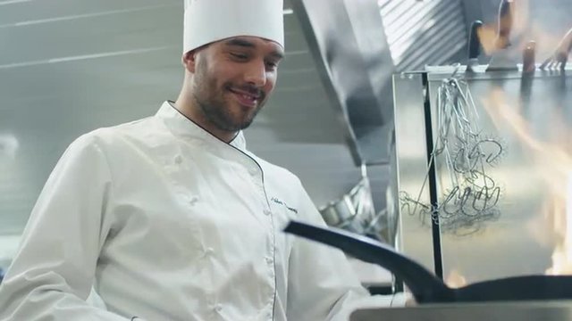 Professional chef in a commercial kitchen is preparing food with fire on a pan. Shot on RED Cinema Camera.
