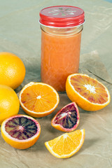 Fresh whole and sliced oranges lying on gray paper.