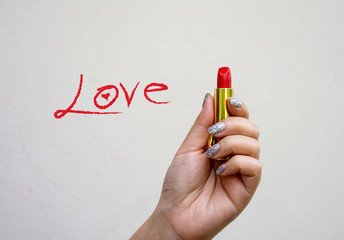 beautiful girl's hand holding a red lipstick on a white backgrou