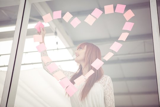 Smiling hipster woman doing a heart in post-it