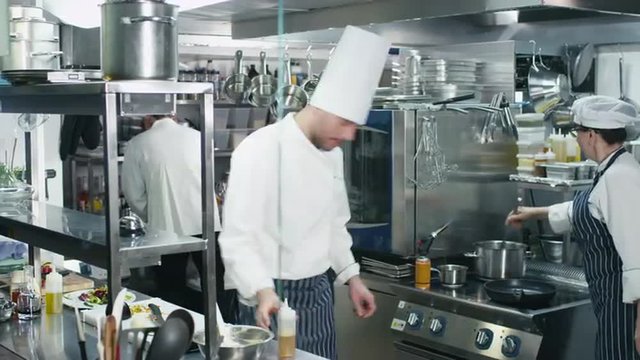 Timelapse footage of three professional chefs in a commercial kitchen in a restaurant or hotel preparing food. Shot on RED Cinema Camera.