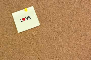 Message LOVE and heart icon on Note Paper on cork board.