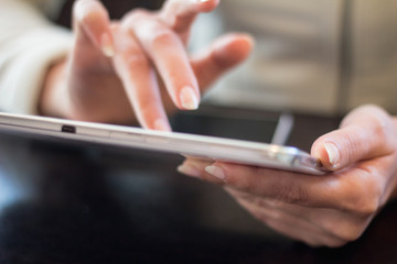 woman holds a smartphone telephone, works on the digital tablet, soft focus, close up