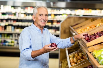 Smiling senior man holding red onion