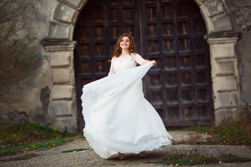 Elegant stylish sweet young beautiful happy bride in amazing wedding dress stands on the old palace. Wedding day
