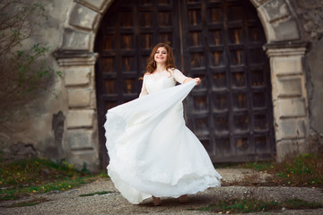 Fototapeta premium Elegant stylish sweet young beautiful happy bride in amazing wedding dress stands on the old palace. Wedding day
