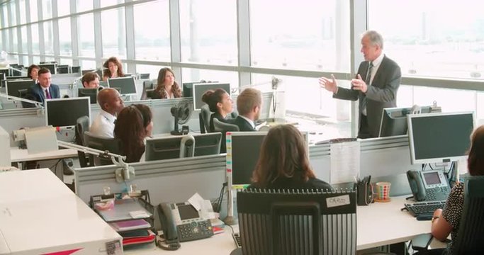 Senior male manager addressing workers in open plan office