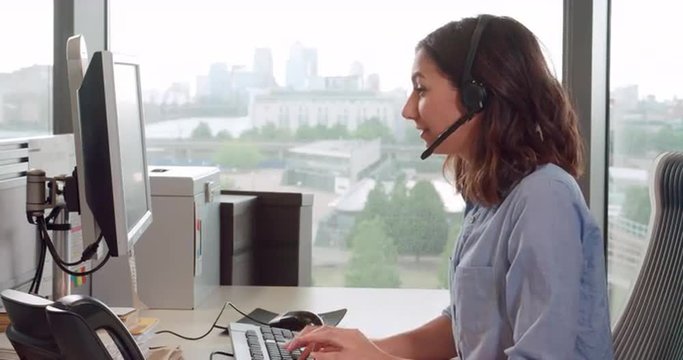 Young female call centre worker wearing headset, side view