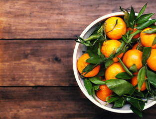 Fresh mandarine tangerine clementines in white bowl over wooden