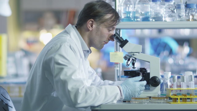 Male scientist is working on a microscope in a laboratory. Shot on RED Cinema Camera.