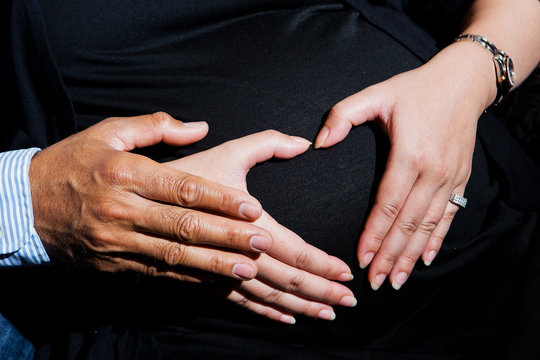 Closeup of pregnant woman holding her hands on her swollen belly