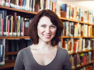 Closeup portrait of smiling happy  middle age mature woman student in library looking directly in camera, teacher librarian profession, back to school concept