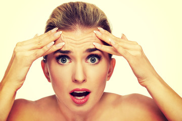A young woman checking wrinkles on her forehead