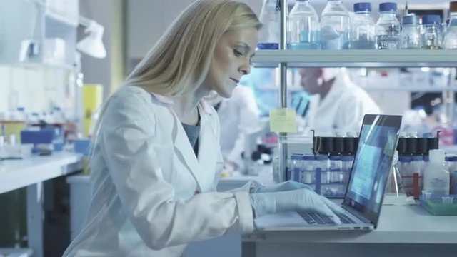 Female scientist is using a laptop computer while working in a laboratory. Shot on RED Cinema Camera.