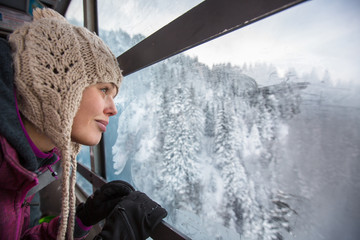 Pretty, young woman admiring splendid winter scenery from a cabl