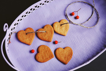 Heart shaped biscuits with ash berries on a lilac tray, top view