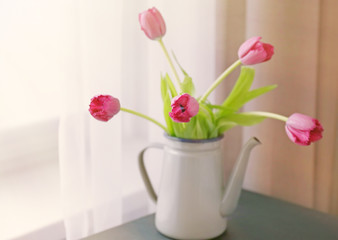 Tulips in watering can on the table, close up