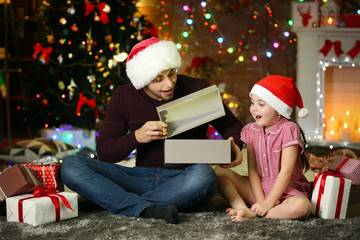 Fototapeta na wymiar Older brother and little sister in Santa hat opening gift on Christmas background