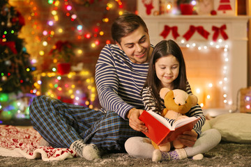 Older brother with little sister reading fairy tale in Christmas living room