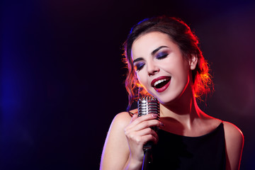 Portrait of beautiful singing woman on dark background