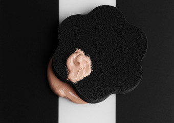 Makeup sponge with liquid foundation on abstract background