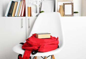 Red backpack with book on white chair