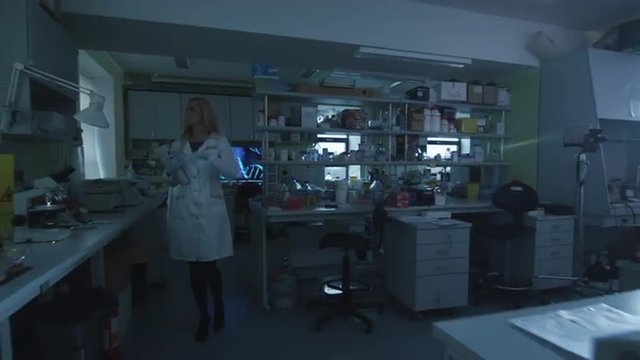Blond female scientist is coming to the laboratory and turning the lights on. Shot on RED Cinema Camera.