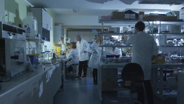 Group of caucasian scientists in white coats are working in a modern laboratory. Shot on RED Cinema Camera.