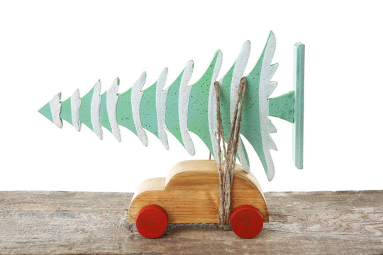 Wooden toy car with Christmas tree on a table over white background