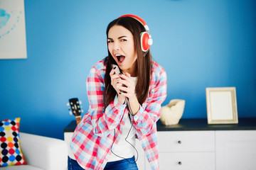 Crazy  young woman with headphones listening to music and singing at home