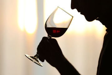 Silhouette of man sniffing red wine in a glass, close up - obrazy, fototapety, plakaty