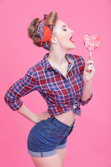 Cute pin-up girl is tasting sweet lollipop