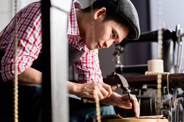 Asian shoe or belt maker in his leather workshop - obrazy, fototapety, plakaty