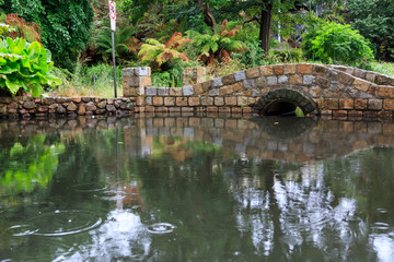 Fototapeta na wymiar Stone arch bridge over pond