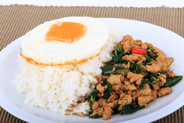 Rice topped with stir-fried chicken, basil and fried egg, fried stir basil with minced chicken on white background (Isolated Background)