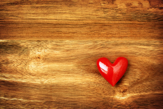 Shiny red heart on wooden background