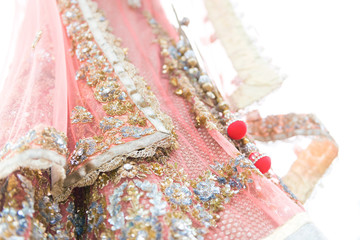 Closeup colourful traditional indian bride dress on white background. Selective focus.