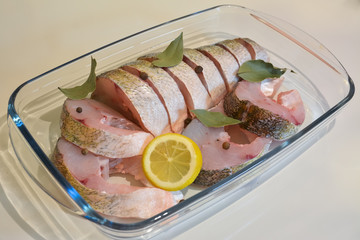 Appetizing slices of fish with lemon, pepper and bay leaf prepar