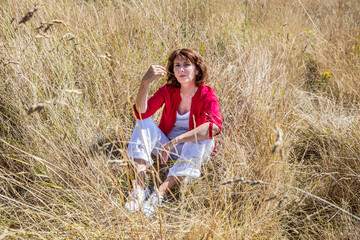 outdoors relaxation - beautiful lady sitting in high dry summer field to enjoy peace and sun,summer daylight...
