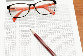 glasses and pencil on Standardized test form with answers bubbled in and a pencil, focus on anser sheet